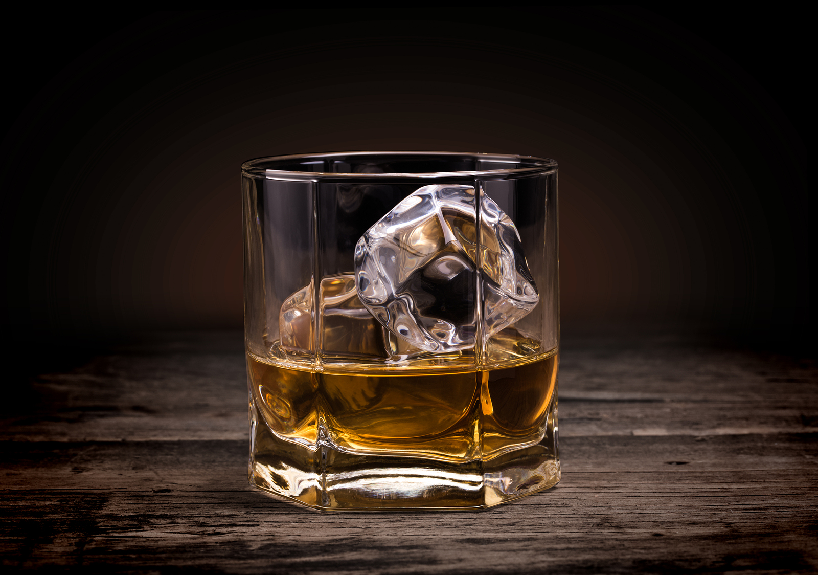 Glasses of whiskey on wood background.